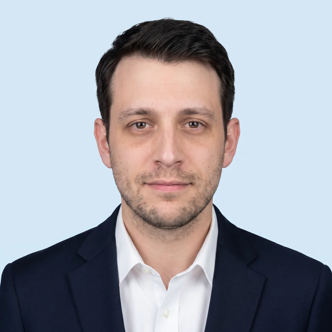 AI-edited formal ID-style photo of the same man in a blazer against a light blue background.