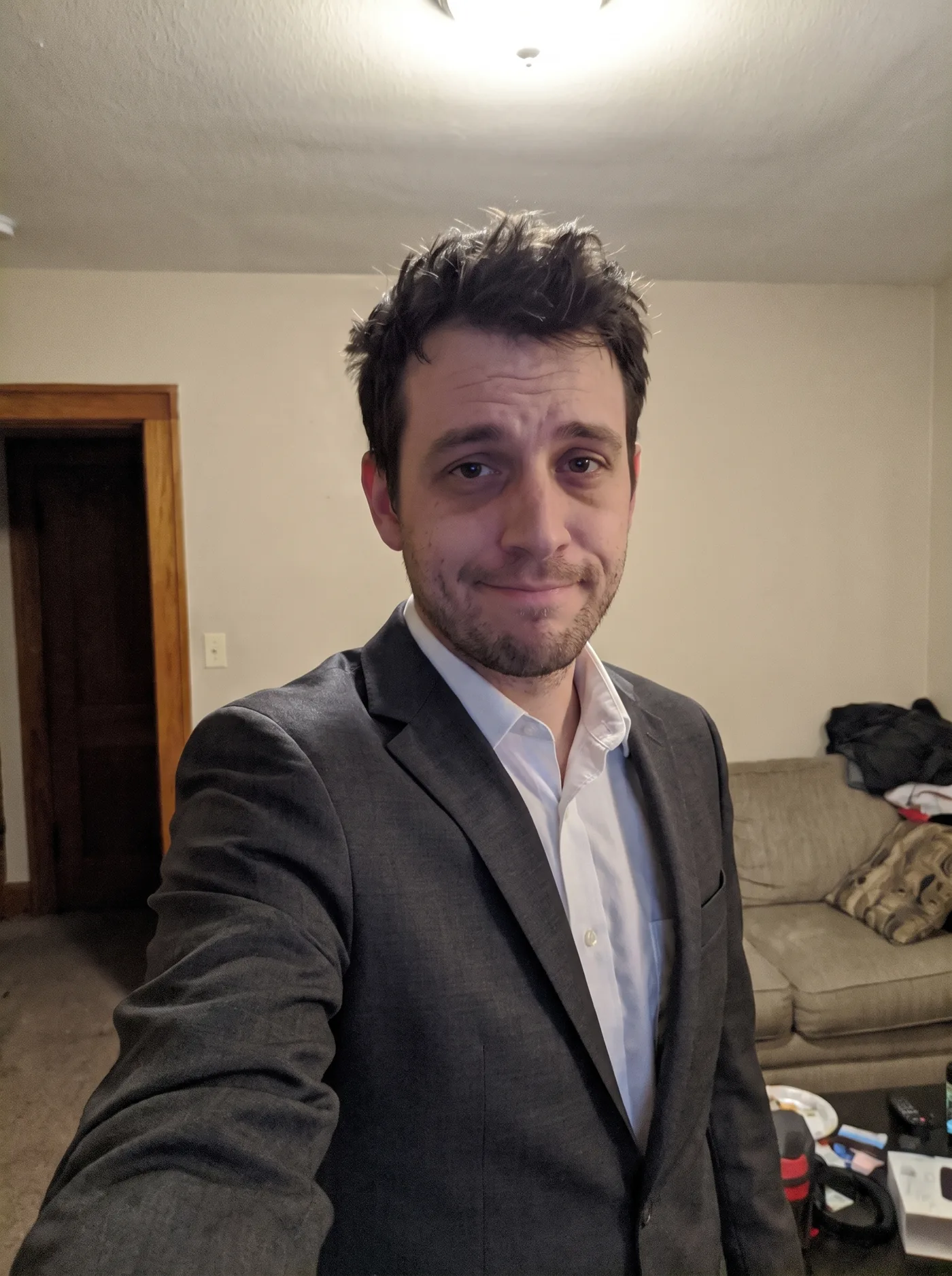 The same selfie with the grey hoodie replaced by a charcoal suit jacket and white shirt.