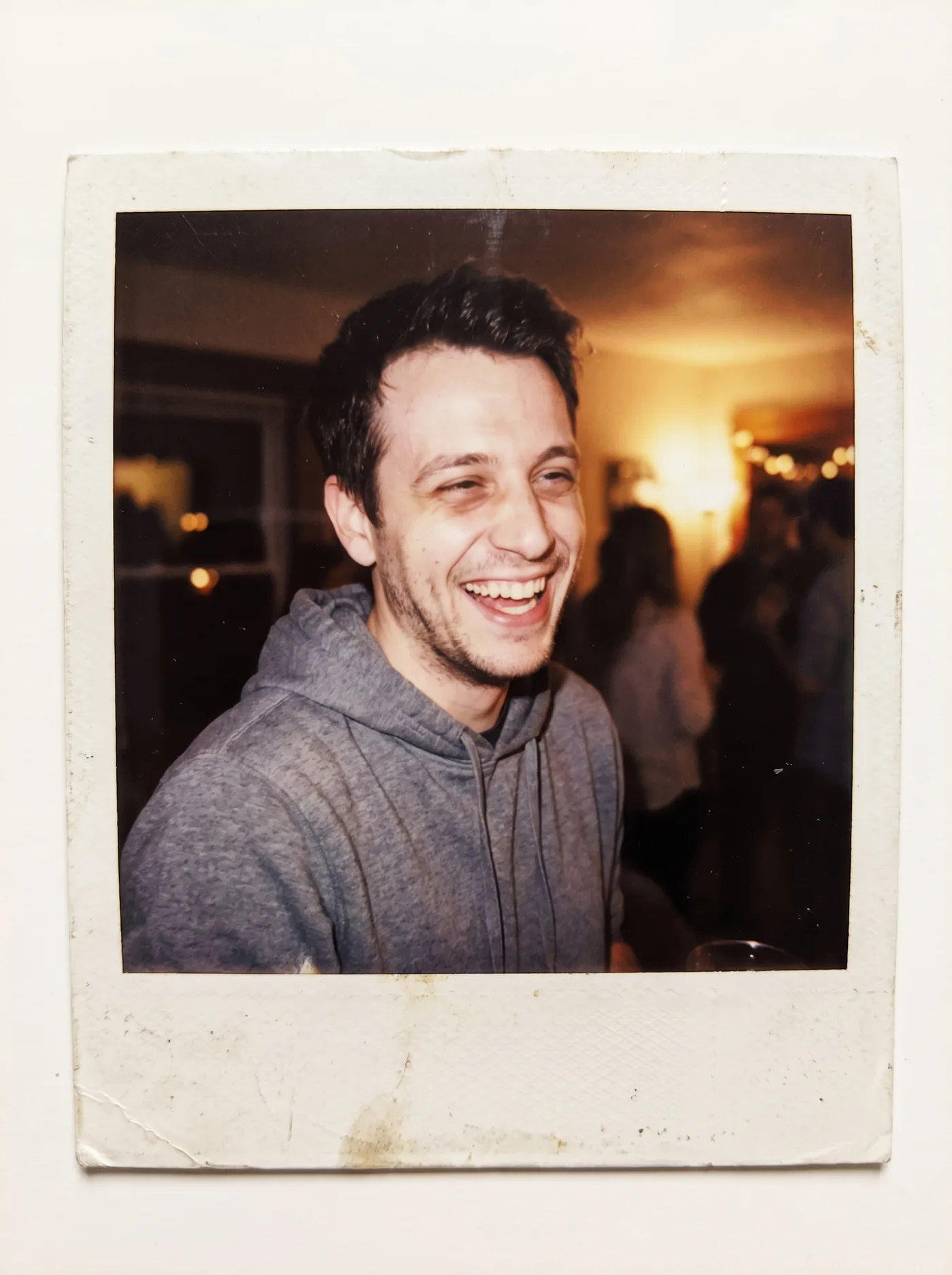 AI-edited instant-camera style photo of the same man laughing, in a white Polaroid-style frame.