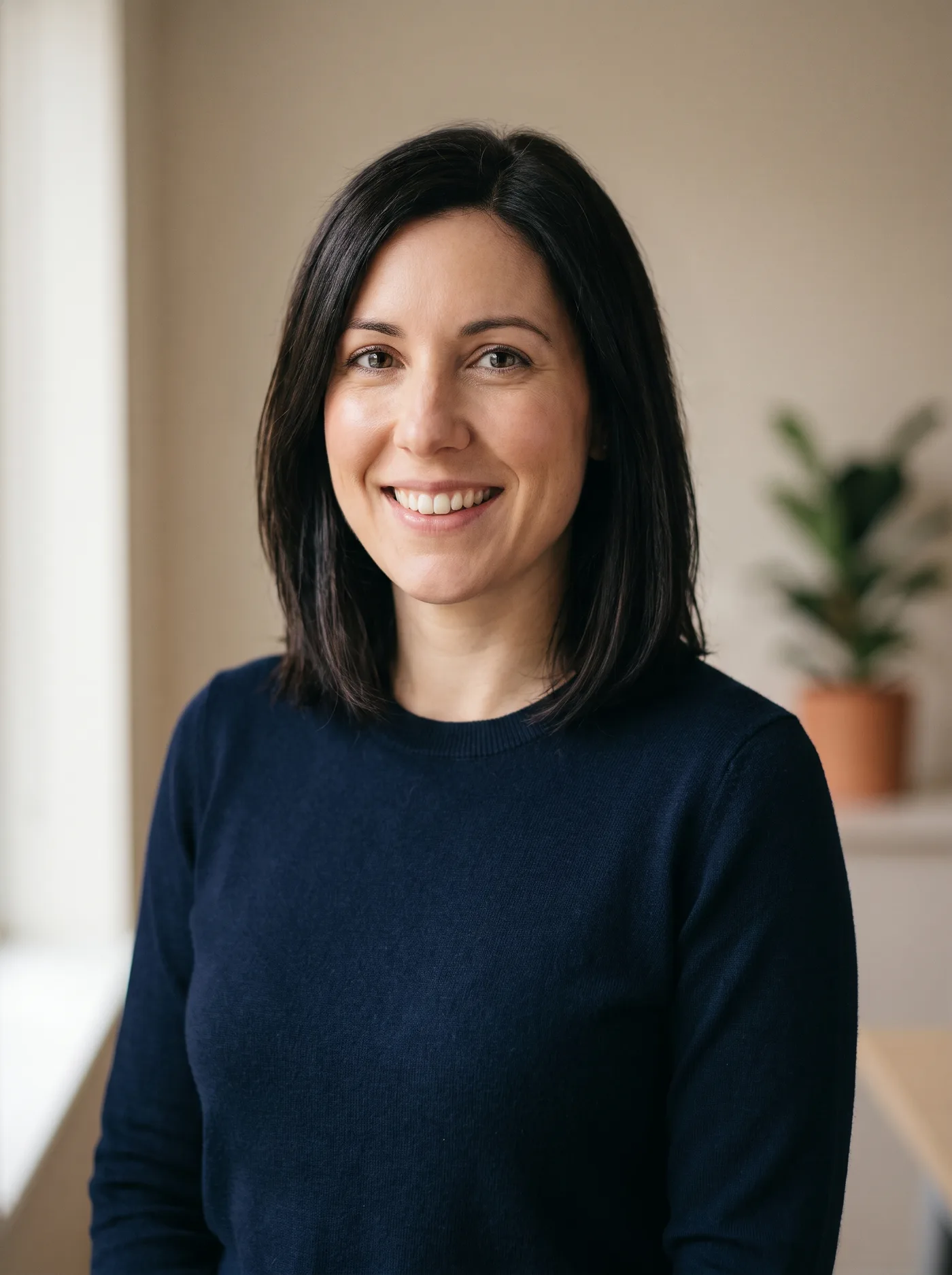 AI-generated friendly business headshot of a woman in a navy jumper against a softly blurred office background.