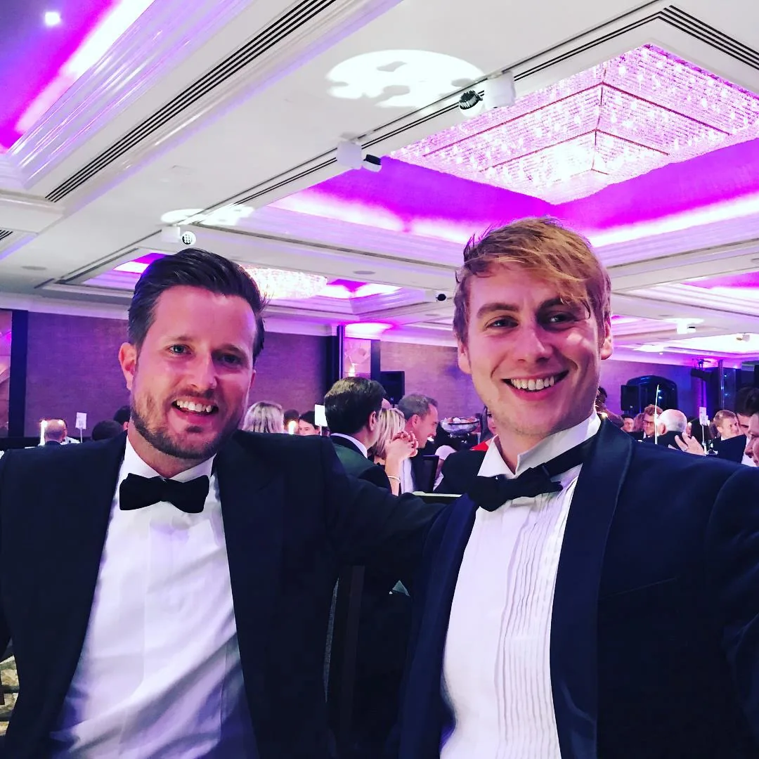 Two of the team in black tie at an awards dinner