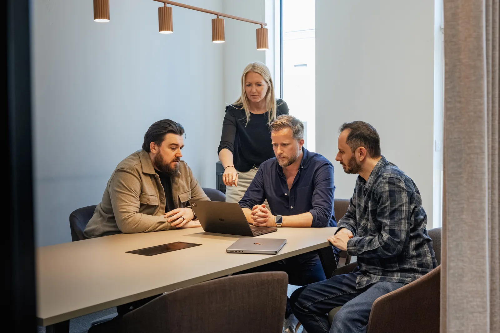Four of the team gathered around a laptop in the studio